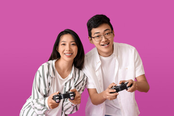 Young Asian friends playing video game on violet background
