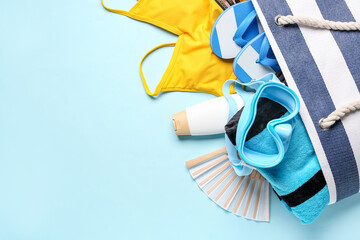 Female bag with different beach accessories on color background