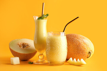 Glasses of tasty melon smoothie with mint on orange background
