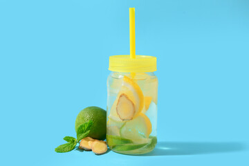 Mason jar of tasty lemonade with ginger and lime on blue background