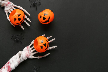 Skeleton hands with pumpkins and spiders for Halloween celebration on dark background