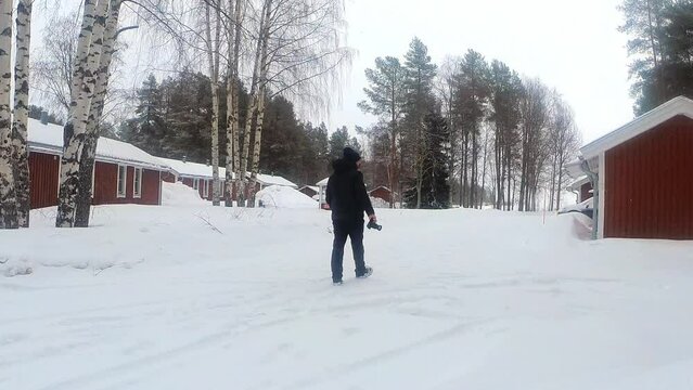 Adventurous photographer man walking while snowing in a winter landscape in Sweden. Winter Tourism.