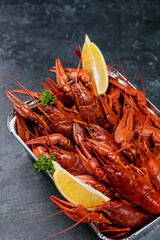 Boiled crayfish with lemon in a bowl on a gray background