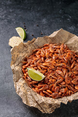 Small shrimps cooked in a bowl with lemon, garlic on a gray background