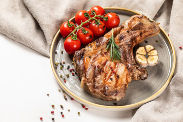 Grilled meat on a wooden board with trimmings on a light background