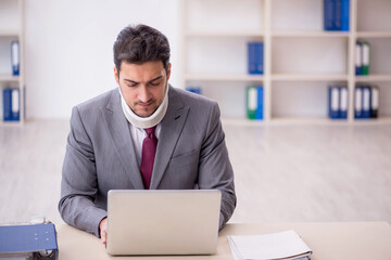 Young male employee after car accident sitting in the office