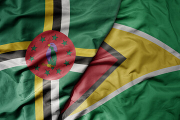 big waving realistic national colorful flag of dominica and national flag of guyana .