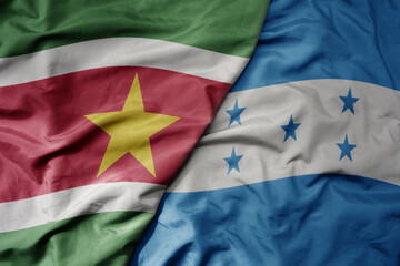 big waving realistic national colorful flag of suriname and national flag of honduras .