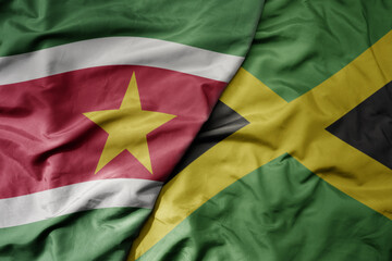 big waving realistic national colorful flag of suriname and national flag of jamaica .