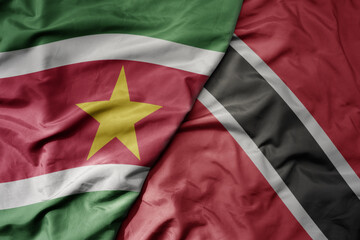 big waving realistic national colorful flag of suriname and national flag of trinidad and tobago .