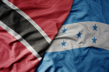 big waving realistic national colorful flag of trinidad and tobago and national flag of honduras .