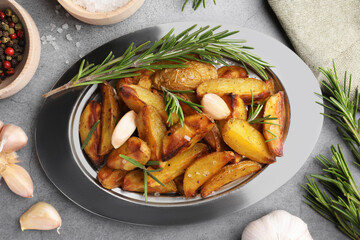Tasty baked potato and aromatic rosemary on grey textured table, flat lay