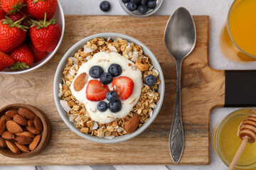 Tasty granola, yogurt and fresh berries served on light table, flat lay. Healthy breakfast