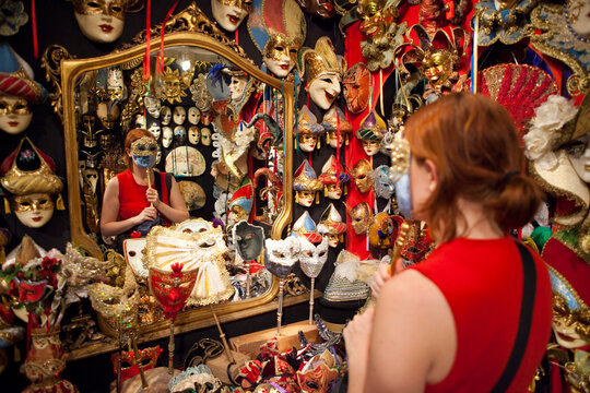 A tourist wears a souvenir painted mask in a shop for Venice Carnival (Carnevale di Venezia).