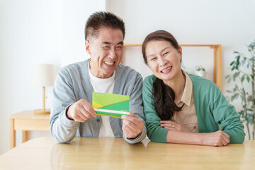 通帳を見て微笑むシニア夫婦