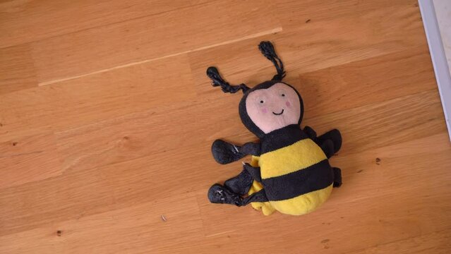 Soft shabby old children toy bee falls on the wooden floor, close-up. Childish whims, bad mood, tantrums, tired of throwing out a toy. Cleaning old children's things, throwing out trash