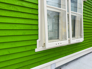 A vibrant lime green color horizontal wooden clapboard siding on the exterior of a house. There are...