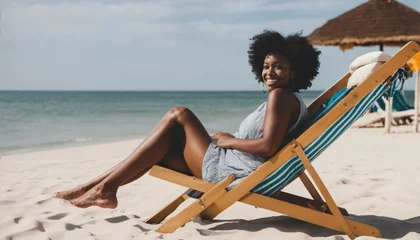  Smiling black woman relaxing on deck chair at beach © ibreakstock
