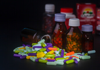 Pills and pill bottles without labels on black background.