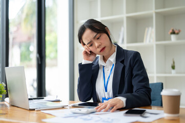 Fototapeta premium A confused Asian businesswoman reading report with a doubtful face, analyzing financial data