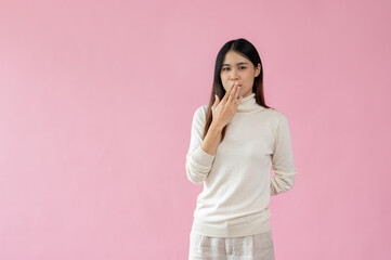 A beautiful Asian woman is covering her mouth and showing a stunned face