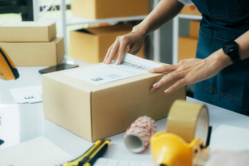 Young business owner putting shipping label on parcel..