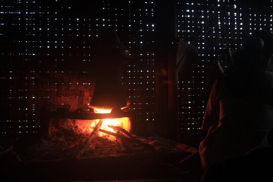 photo illustration of a silhouette of a village woman cooking in a traditional kitchen with a wood-fired stove