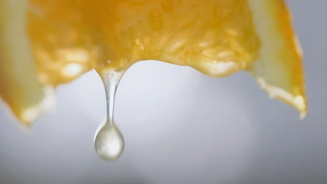 Macro shot, squeezing orange slice, juice drops falling in Slow motion