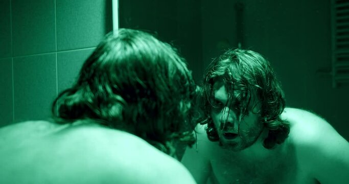 Stressed, depressed man looking at the mirror bathroom. Person in crisis concept. Strong emotional distress. Washing face with cold water. Mental health, man depression. Depressive light