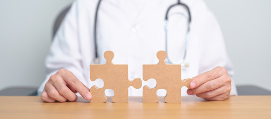 Doctor hand connecting couple puzzle piece, wooden jigsaw in hospital. Teamwork, Idea, Solution,...