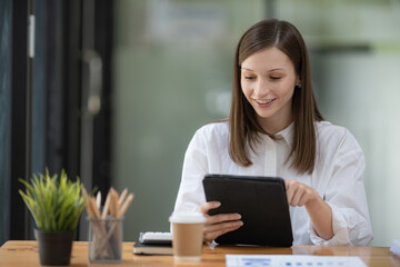 Young Caucasian businesswoman using a tablet at the desk in a modern office.