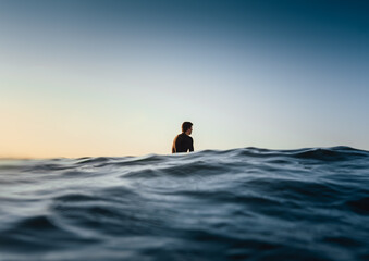 Male surfer being in a calm state while patiently waiting for a wave