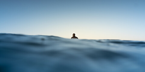 Male surfer being in a calm state while patiently waiting for a wave
