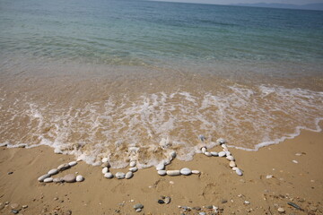 New Year 2024, lettering on the beach with wave and clear blue sea. Numbers 2024 year on the sea...