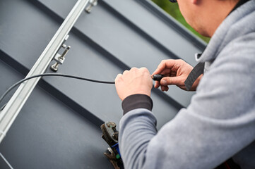 Man worker prepearing for mounting photovoltaic solar modules on roof of house. Electrician in...