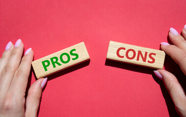 Pros vs Cons symbol. Concept word Pros vs Cons on wooden blocks. Businessman hand. Beautiful red background. Business and Pros vs Cons concept. Copy space