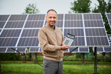 Knowledgeable man glad about his investment in green energy. Happy man showing his future profit...