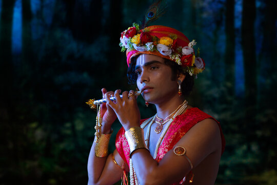 Portrait of young man dressed up as Lord Krishna and playing flute on the occasion of Janmashtami