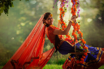 Young woman dressed up as Radha and sitting on a swing on the occasion of Janmashtami