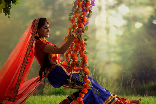 Young woman dressed up as Radha and sitting on a swing on the occasion of Janmashtami
