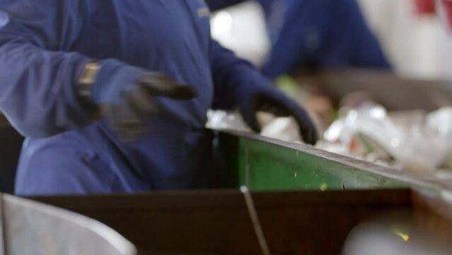 Workers wearing PPE selecting and sorting plastic waste for recycling