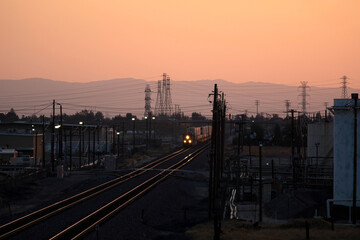 Fototapeta na wymiar Train approaching in industrial area at dusk