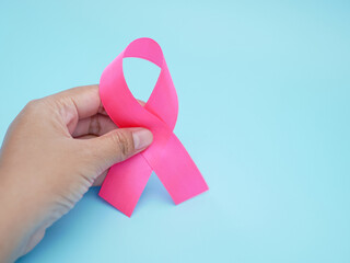 Woman holding teal awareness ribbon against blue background. support to fight cervical cancer.
