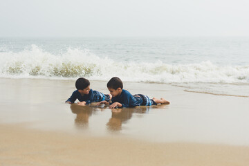 Young boys playing in sand and waves on beach. © Cavan
