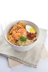 spicy nyonya noodlel malay laksa mee soup with seafood prawn, fish cake, egg, bean curd and chilli sambal thick gravy sauce in bowl on white background asian halal food cuisine menu for cafe design