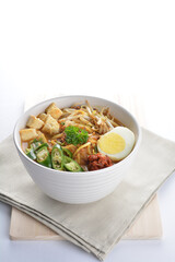 Malay mee rebus noodle with boiled egg, tofu, green chilli, sambal, vegetable, chilli sauce and hot thick spicy gravy soup in bowl on white background asian halal food cuisine menu for cafe design