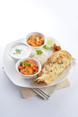 Indian traditional baked roti prata canai with curry vegetables, yogurt sauce, pea bean and steamed white rice  in plate on white background asian halal food vegan cuisine menu for cafe design
