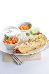 Indian traditional baked roti prata canai with curry vegetables, yogurt sauce, pea bean and steamed white rice  in plate on white background asian halal food vegan cuisine menu for cafe design