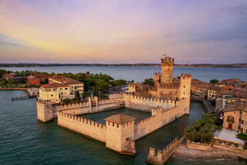 Naklejka premium The beautiful coastline of Sirmione in Italy on Lake Garda at sunrise. The historic Scaliger Castle.