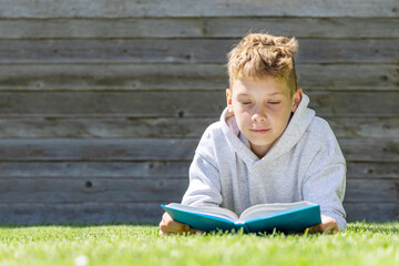 A boy reading a book on a grass